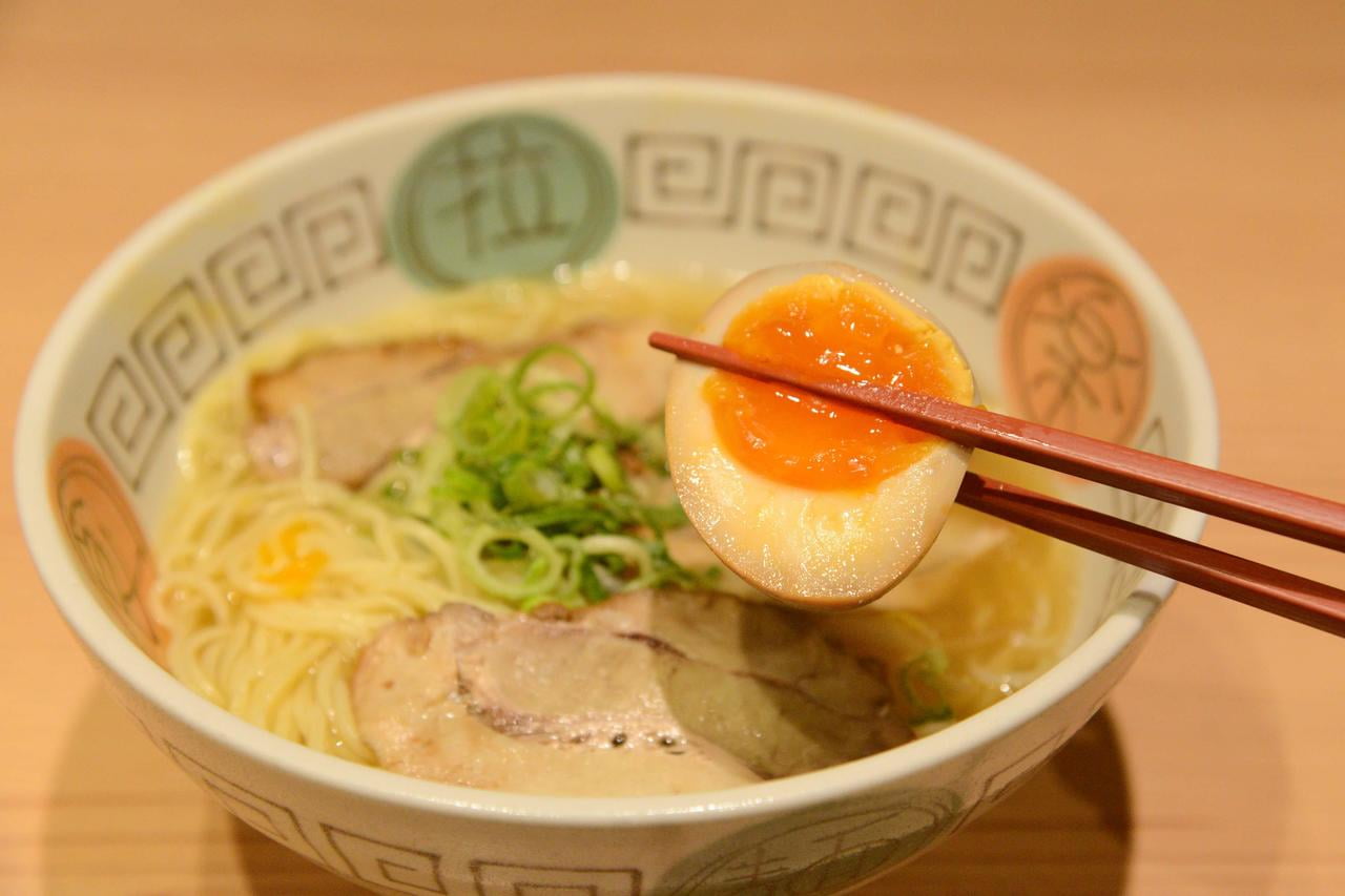 天馬らぁめんの塩ラーメンのトッピング味付けたまごを持ち上げている写真.jpg