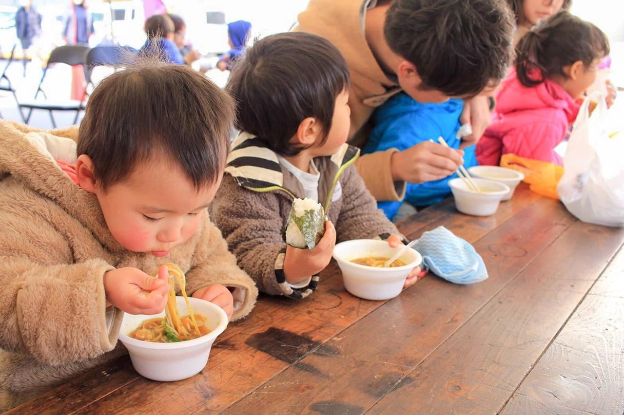 ふれあい麺まつりで行われる無料試食の温かい麺をおいしそうに食べる子どもたちの写真
