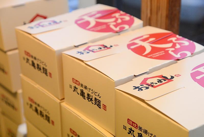 揚げ立て天ぷらを持ち帰る用の箱が積み上げられた写真