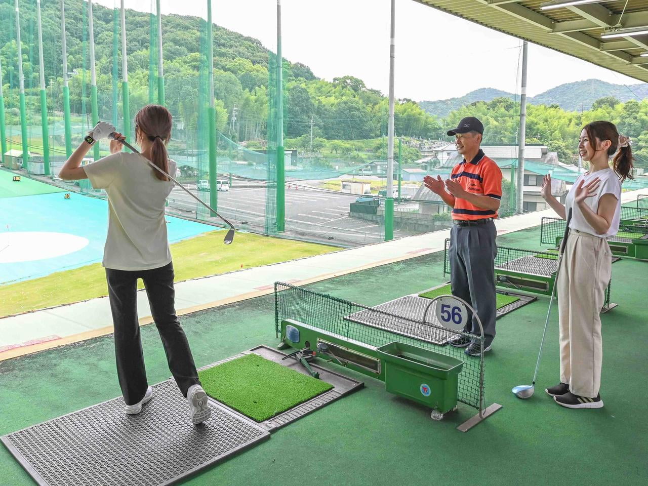 打席で長久さんがうち、コーチと大西が笑顔で見ている写真