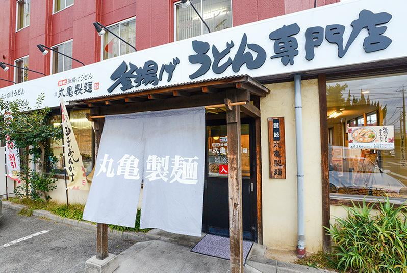 2000年に加古川にオープンした丸亀製麺第一号店創業当時のままの看板や柱の年季に歴史を感じる外観写真