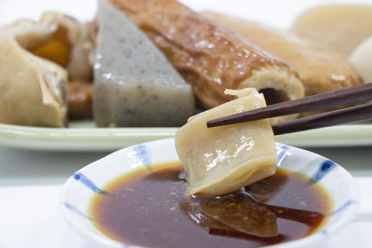 姫路おでんの特徴である生姜醤油を小皿に入れ、牛すじをつけている写真